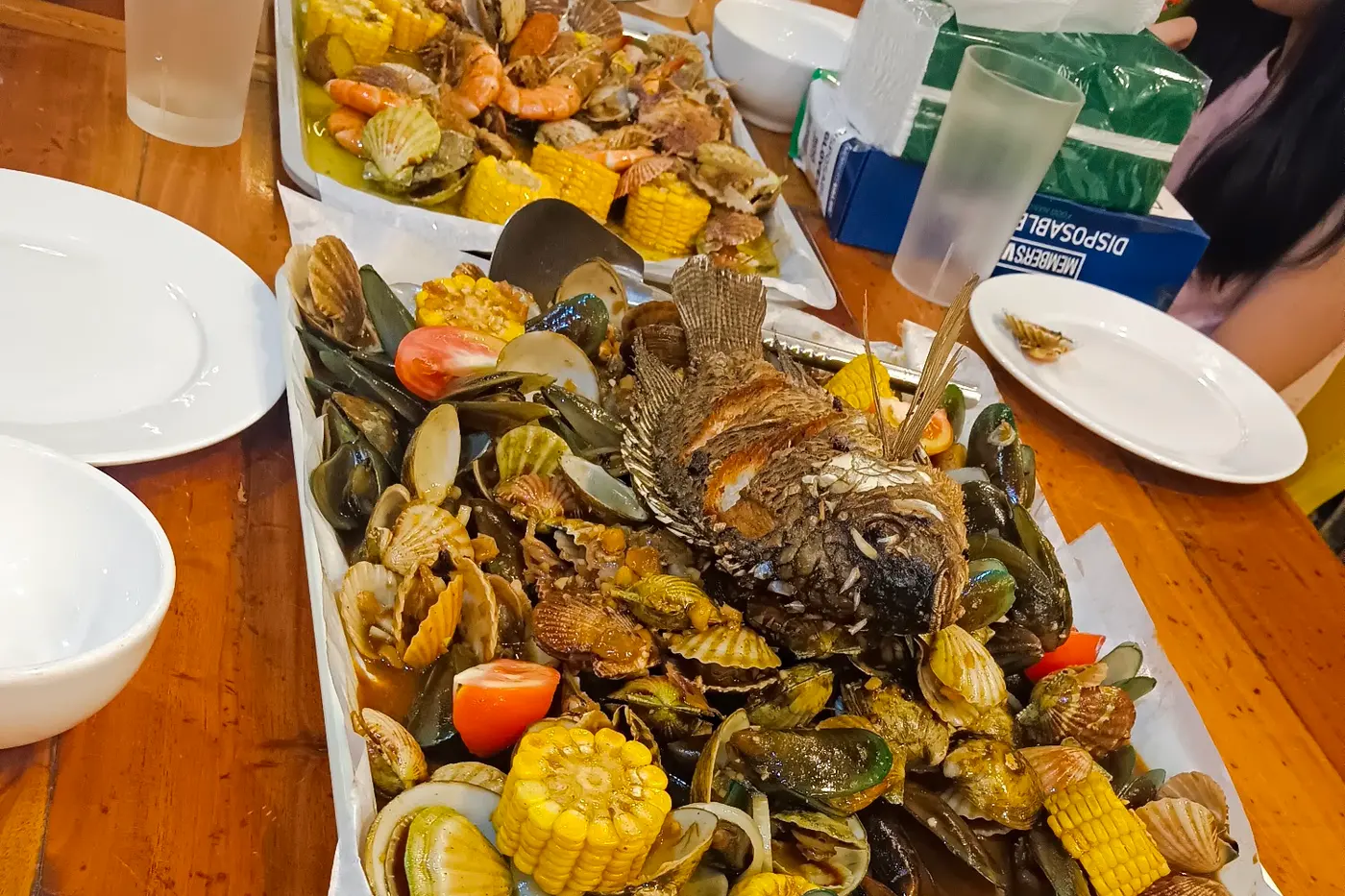 A tray of mussels, clams and corn in sauce