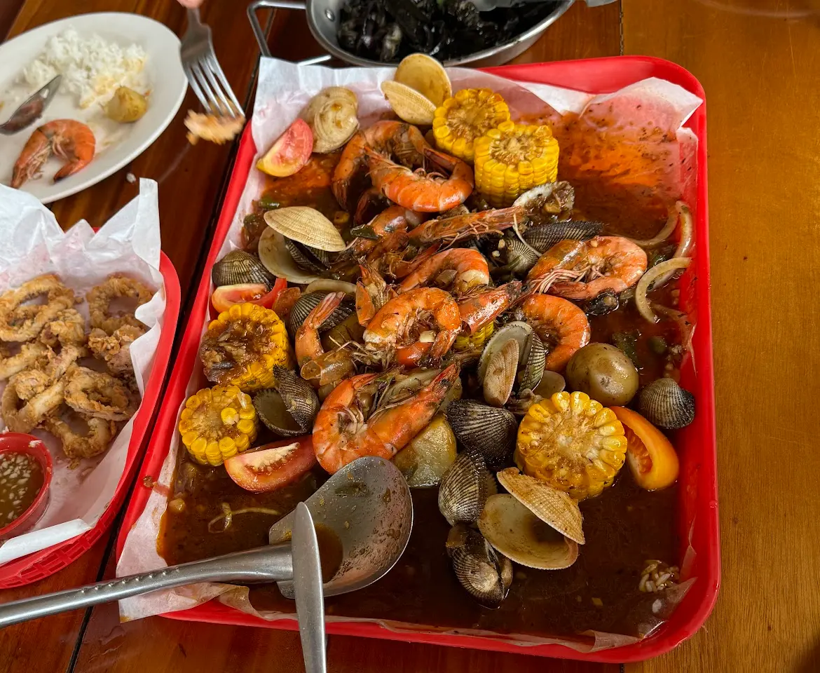A red tray of shrimp, clams, corn and potatoes