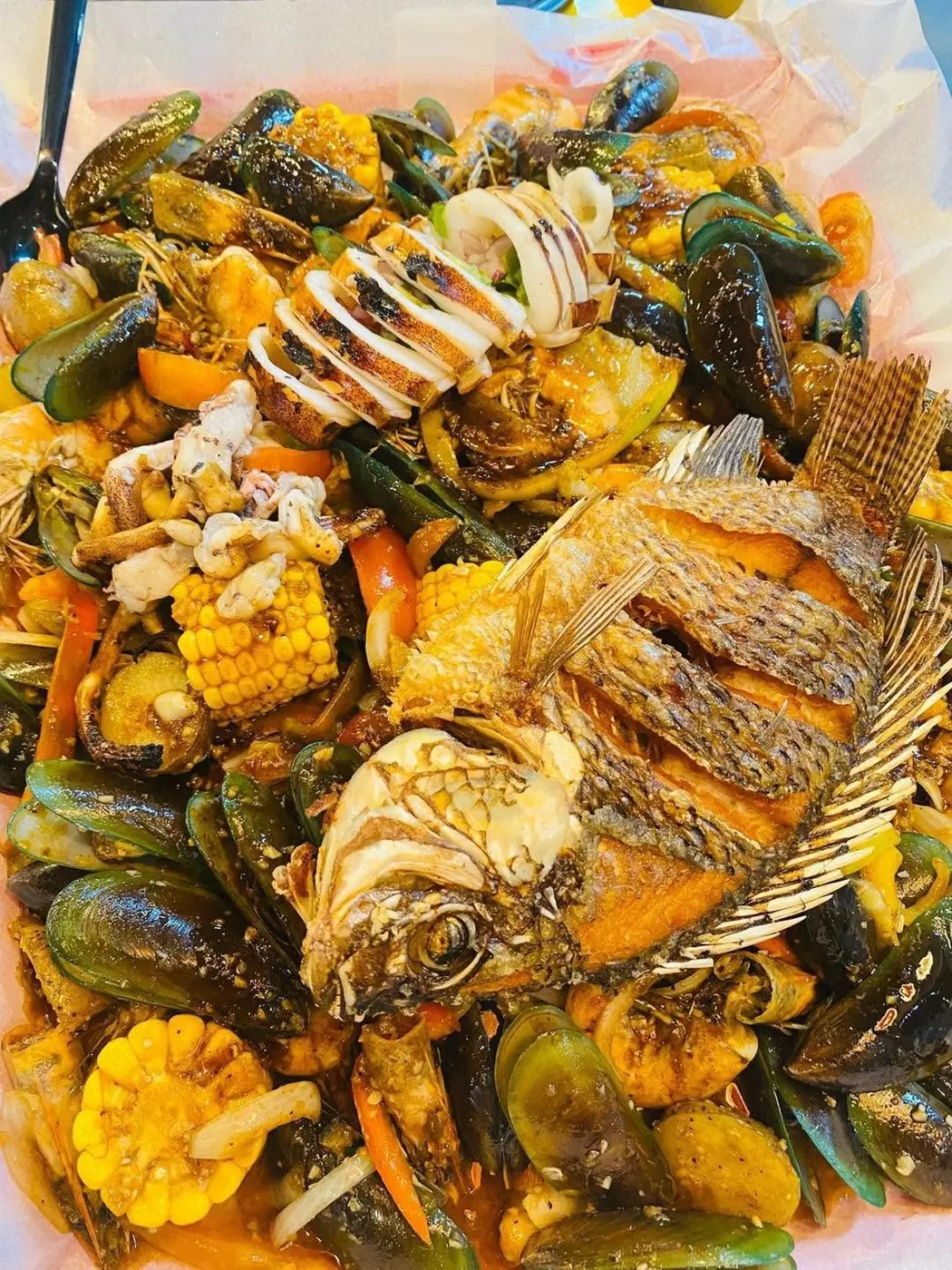 Fried tilapia, squid rings, mussels and corn piled on one tray